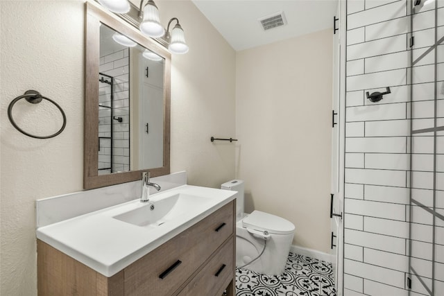 bathroom with tile patterned flooring, vanity, toilet, and tiled shower