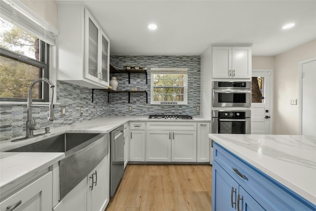 kitchen with light wood-type flooring, white cabinetry, blue cabinets, and a wealth of natural light