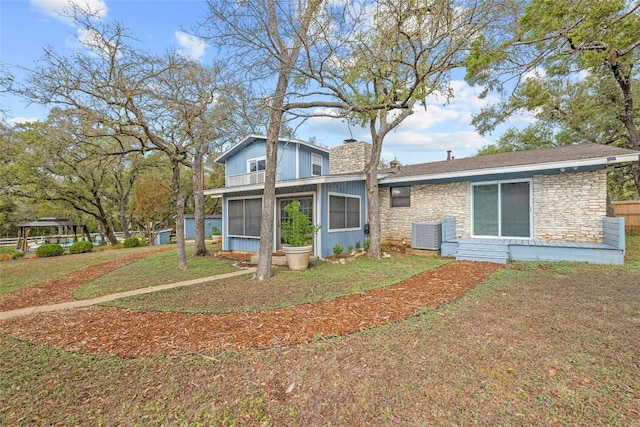 view of front of house featuring a front lawn, cooling unit, and a sunroom