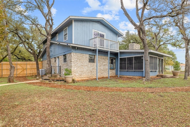 back of house with a lawn, a sunroom, and a balcony