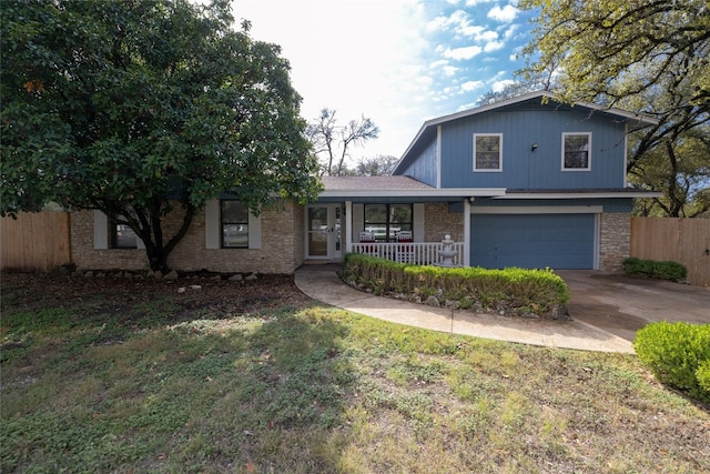 view of front of home featuring covered porch, a garage, and a front yard