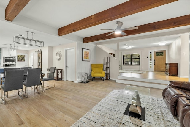 living room with beamed ceiling, light hardwood / wood-style floors, and ceiling fan