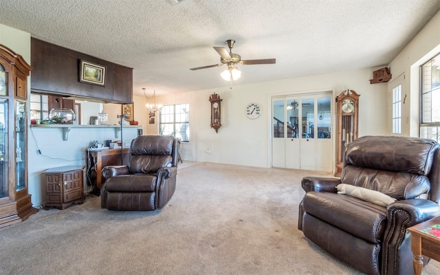 carpeted living room featuring ceiling fan with notable chandelier and a textured ceiling