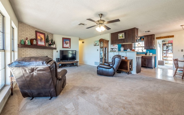 carpeted living room featuring ceiling fan, sink, and a textured ceiling