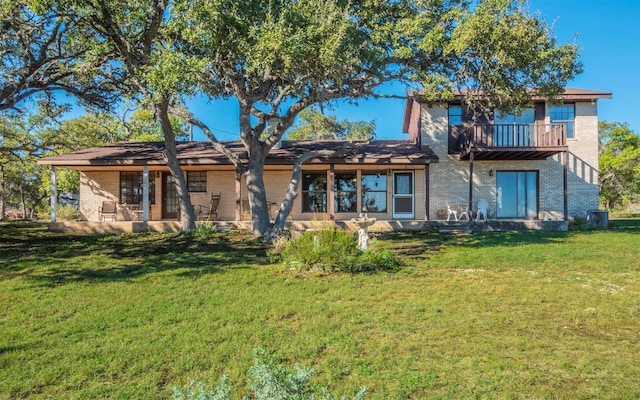 rear view of house with central air condition unit, a balcony, a patio, and a lawn