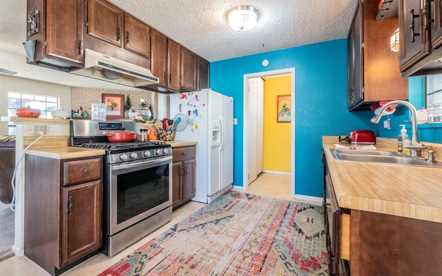 kitchen featuring white fridge with ice dispenser, sink, stainless steel gas range, a textured ceiling, and dark brown cabinets