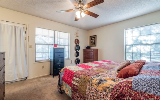 bedroom with multiple windows, light carpet, a textured ceiling, and ceiling fan