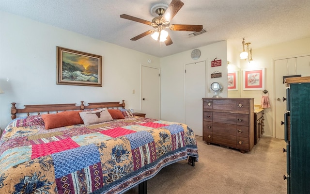 bedroom featuring ceiling fan, light carpet, and a textured ceiling