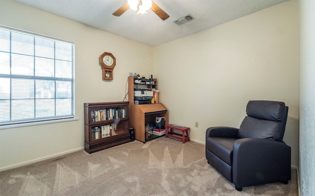 living area featuring a textured ceiling, ceiling fan, and light carpet