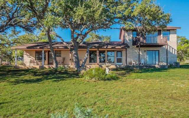 back of property featuring a lawn and a balcony