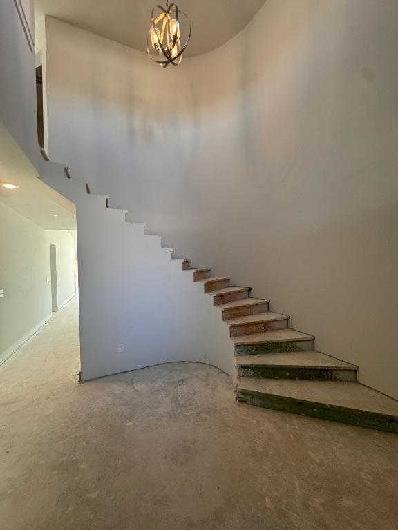 staircase with concrete floors and a chandelier