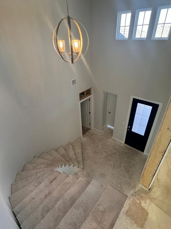 foyer with visible vents, an inviting chandelier, and a towering ceiling