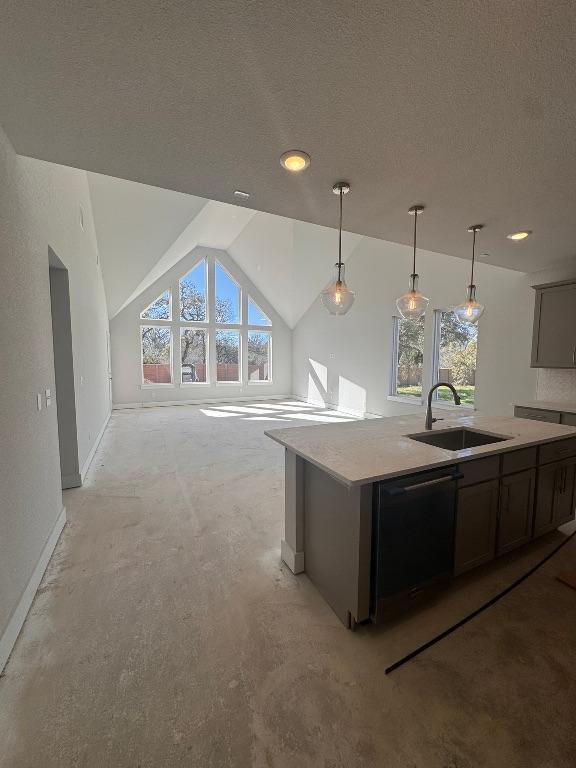 kitchen with an island with sink, a sink, a textured ceiling, light countertops, and dishwashing machine