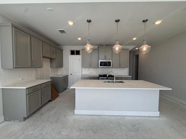 kitchen featuring stainless steel microwave, visible vents, gray cabinetry, unfinished concrete flooring, and a sink