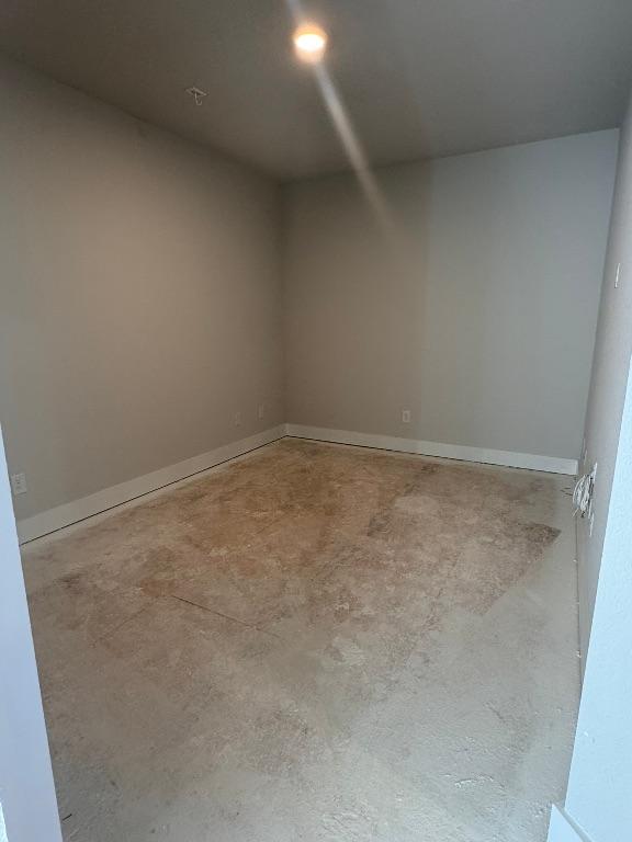 spare room featuring baseboards and concrete flooring