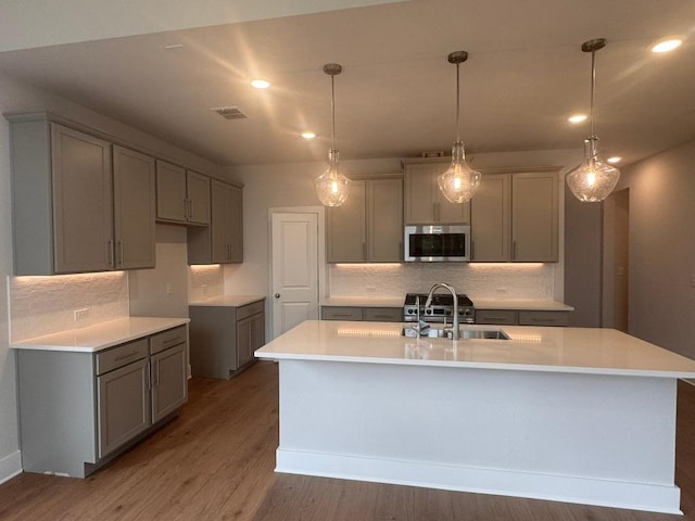 278 Smithsonian Ln, Kyle, TX 78640 - kitchen with stainless steel microwave, decorative backsplash, gray cabinets, wood finished floors, and recessed lighting