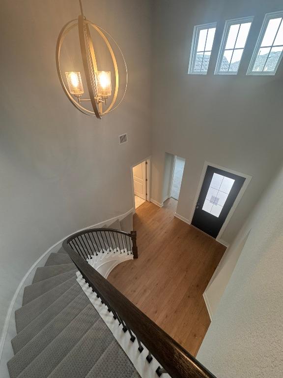 278 Smithsonian Ln, Kyle, TX 78640 - stairs featuring a chandelier, a towering ceiling, and wood finished floors