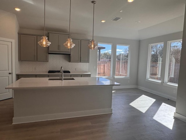 kitchen with visible vents, gray cabinets, a sink, backsplash, and dark wood finished floors