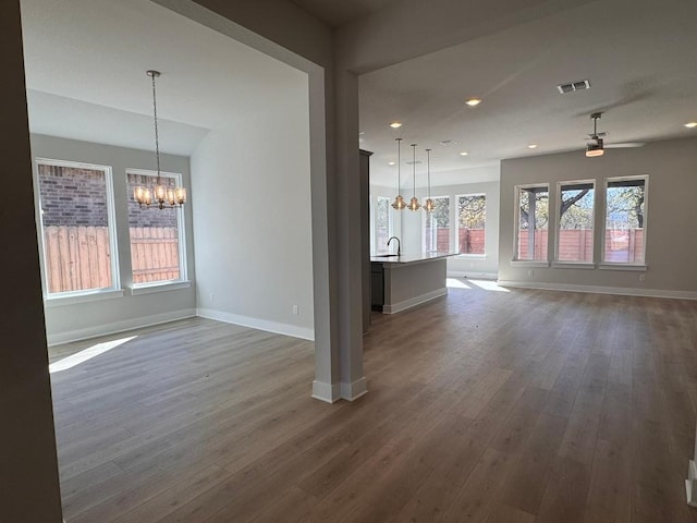 unfurnished living room with visible vents, baseboards, and dark wood-style flooring