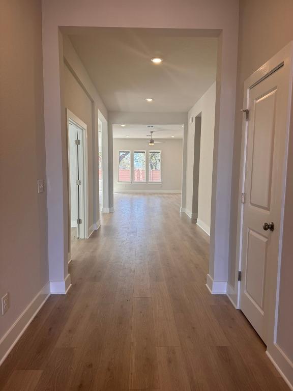 corridor featuring recessed lighting, baseboards, and wood finished floors