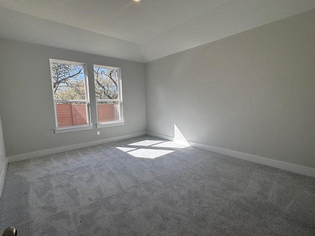 empty room with baseboards, carpet flooring, and vaulted ceiling