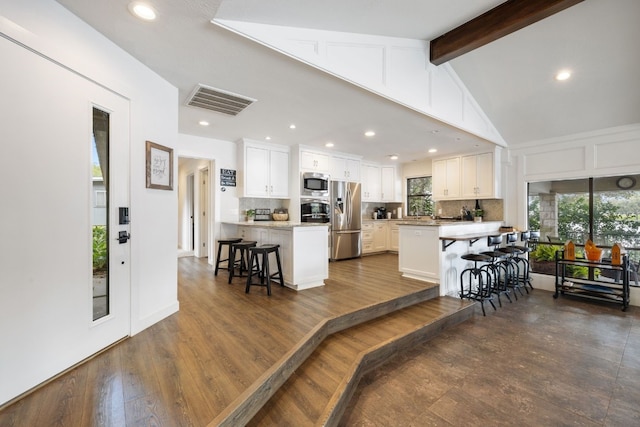 kitchen featuring a kitchen breakfast bar, dark hardwood / wood-style flooring, white cabinets, and appliances with stainless steel finishes