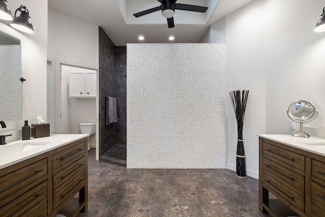 bathroom with vanity, ceiling fan, toilet, tiled shower, and tile walls