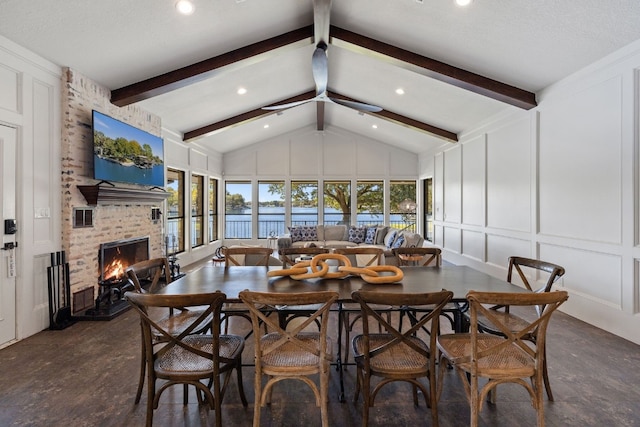 dining space featuring a fireplace, a textured ceiling, and lofted ceiling with beams