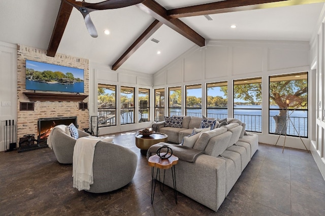 living room featuring a fireplace, a water view, a healthy amount of sunlight, and high vaulted ceiling