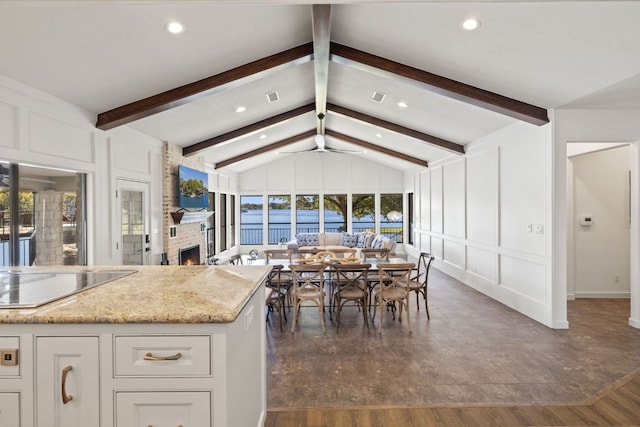 kitchen featuring dark wood-type flooring, electric cooktop, white cabinets, vaulted ceiling with beams, and light stone countertops