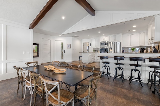 dining space featuring vaulted ceiling with beams