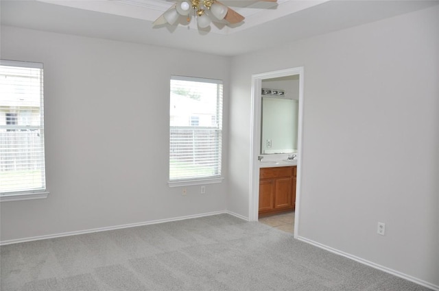 12817 Paloma Blanca Way, Del Valle, TX 78617 - unfurnished bedroom with light carpet, multiple windows, ensuite bathroom, and ceiling fan