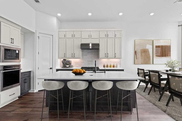 2109 Tobiano Trce, Georgetown, TX 78633 - kitchen featuring stainless steel oven, under cabinet range hood, built in microwave, light countertops, and a sink
