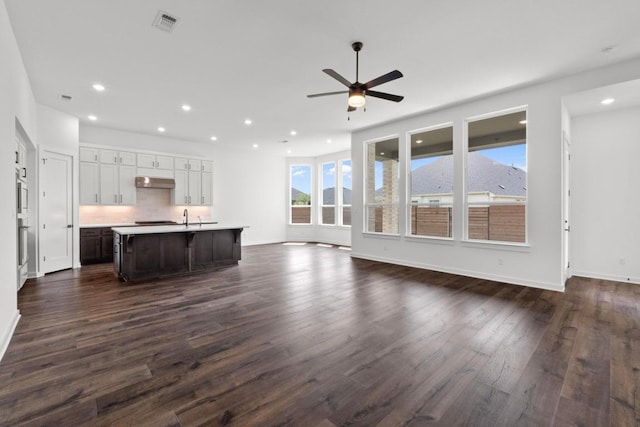 2109 Tobiano Trce, Georgetown, TX 78633 - unfurnished living room featuring a ceiling fan, dark wood-style flooring, recessed lighting, a sink, and baseboards