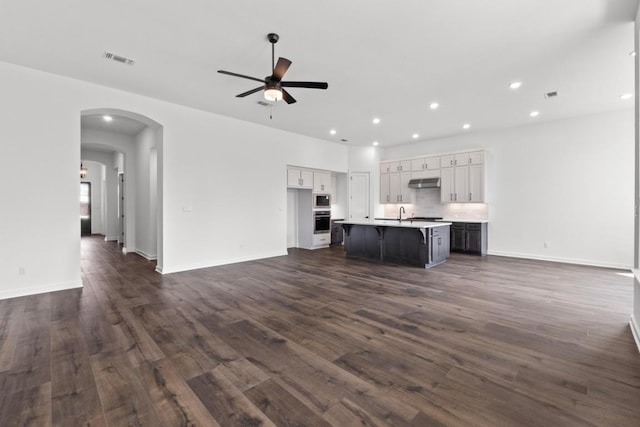 2109 Tobiano Trce, Georgetown, TX 78633 - unfurnished living room featuring ceiling fan, dark wood-type flooring, recessed lighting, baseboards, and arched walkways