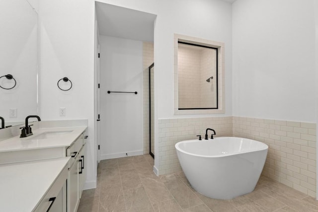 2109 Tobiano Trce, Georgetown, TX 78633 - bathroom with vanity, a shower stall, a freestanding bath, a wainscoted wall, and tile walls