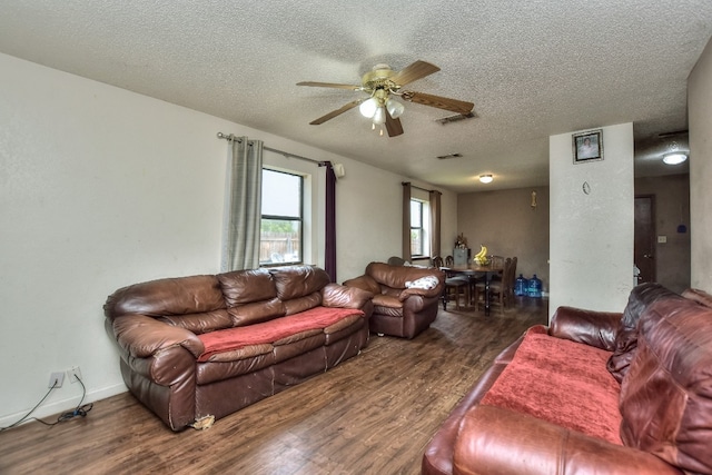 living room featuring ceiling fan, dark hardwood / wood-style flooring, and a textured ceiling