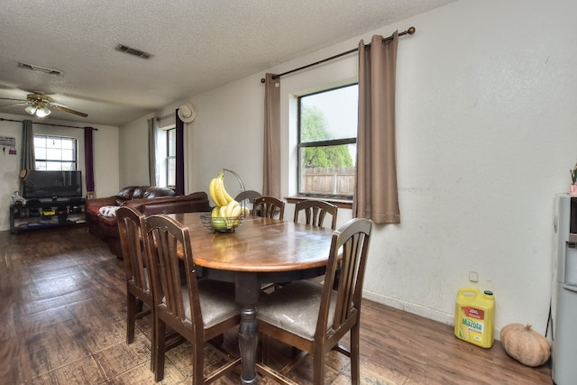 dining area with ceiling fan, dark hardwood / wood-style flooring, and a textured ceiling