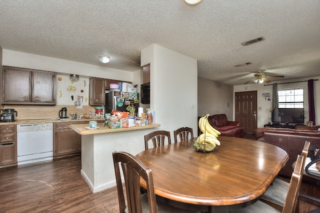 dining space featuring a textured ceiling, ceiling fan, and dark wood-type flooring