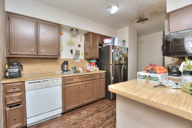 kitchen with stainless steel fridge, tasteful backsplash, a textured ceiling, sink, and dishwasher