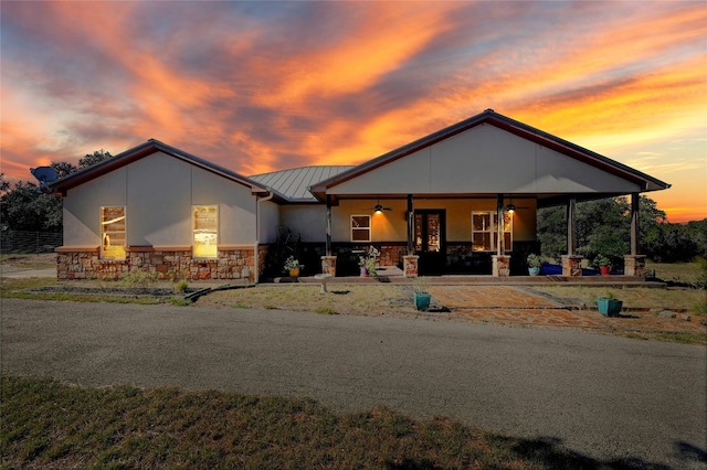 view of front of home featuring a standing seam roof, ceiling fan, stucco siding, stone siding, and metal roof