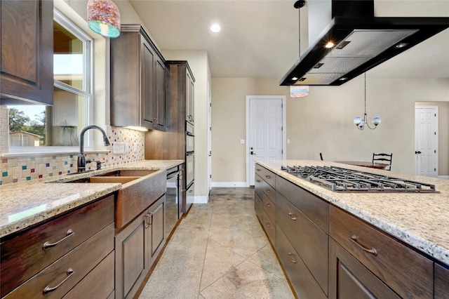 kitchen featuring tasteful backsplash, exhaust hood, light stone counters, and stainless steel gas stovetop