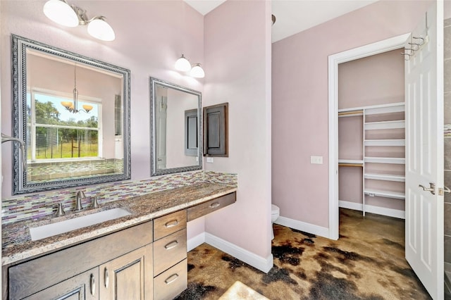 full bath with vanity, baseboards, a spacious closet, toilet, and backsplash