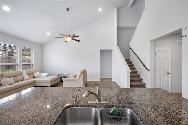 kitchen with ceiling fan, sink, high vaulted ceiling, dark stone countertops, and wood-type flooring