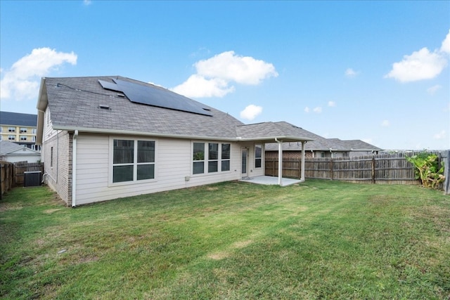 rear view of property with a lawn, a patio area, central AC unit, and solar panels