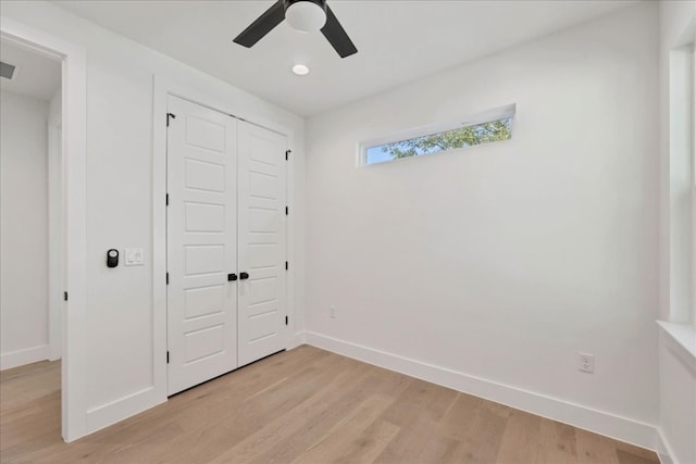 unfurnished bedroom featuring ceiling fan, light hardwood / wood-style floors, and a closet