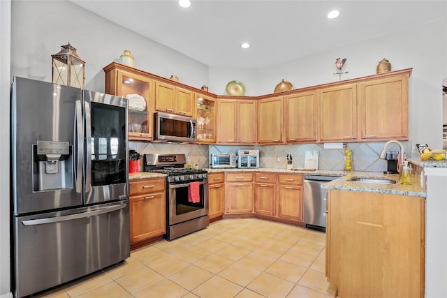 kitchen with sink, decorative backsplash, light tile patterned floors, light stone counters, and stainless steel appliances