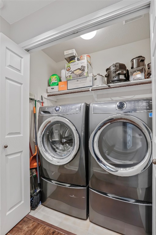 clothes washing area with separate washer and dryer and light hardwood / wood-style flooring