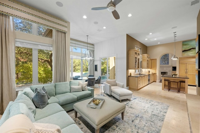 living room with ceiling fan with notable chandelier and sink