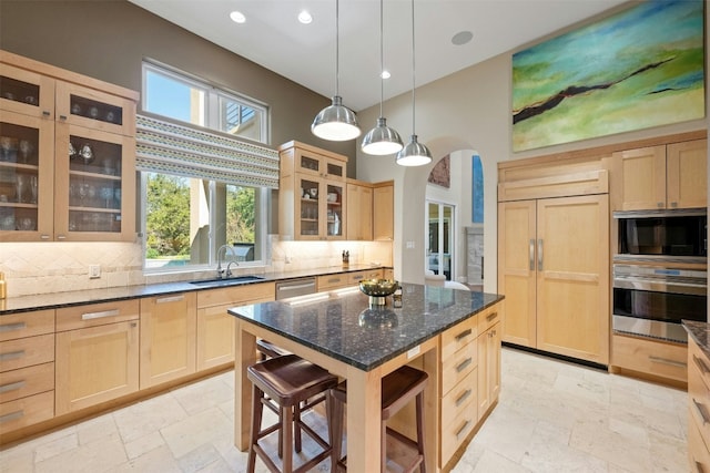 kitchen featuring dark stone counters, sink, light brown cabinetry, tasteful backsplash, and stainless steel appliances